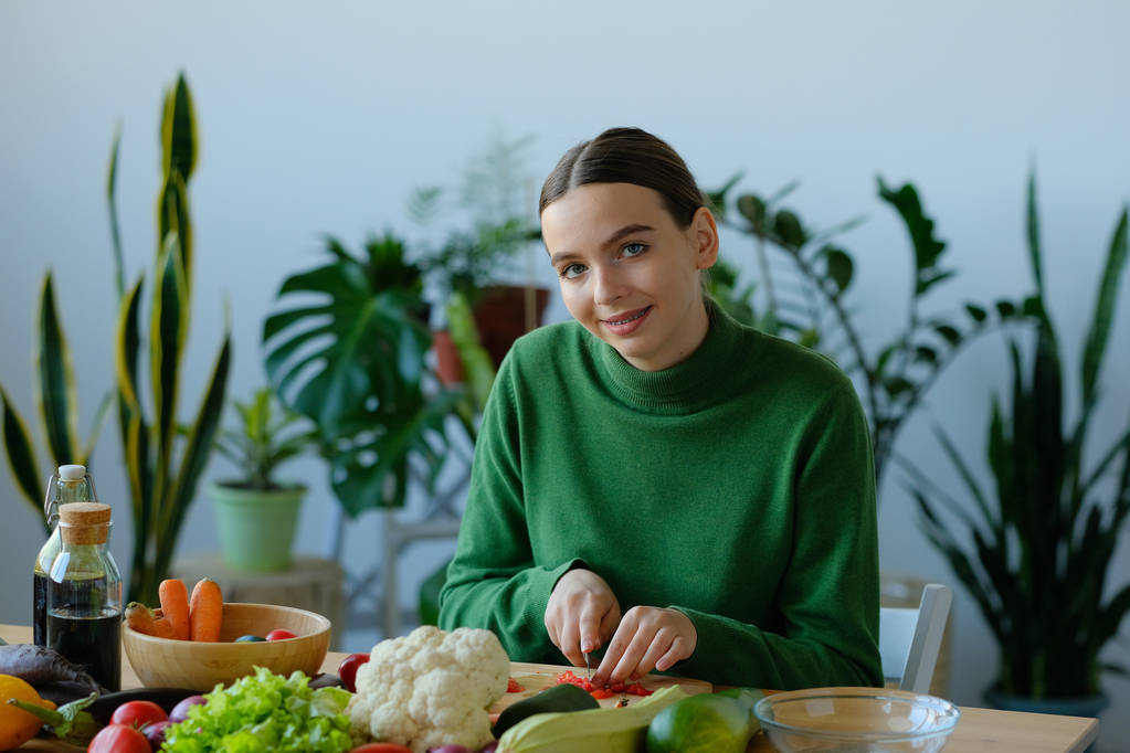 joyeuse fille végétalienne couper des tomates avec couteau à l'intérieur de la maison
 - Photo, image
