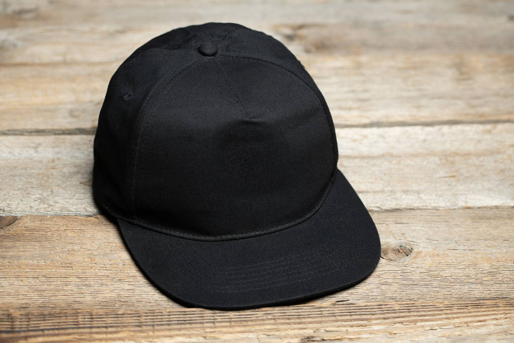 Zwarte Baseballpet voor mock up of uw logo over houten achtergrond - Foto, afbeelding