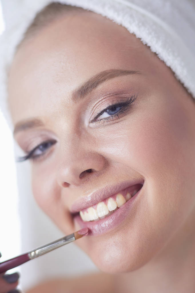 Una foto de una mujer joven aplicando polvo facial en el baño
 - Foto, imagen