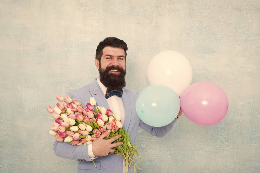 Gentleman romantic date. Birthday greetings. Flowers delivery. For someone special. Man bearded gentleman suit bow tie hold air balloons and bouquet. Gentleman making romantic surprise for her - Photo, Image