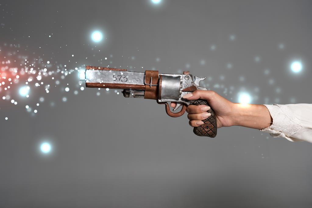 vista cortada de mulher segurando revólver vintage isolado em cinza
 - Foto, Imagem