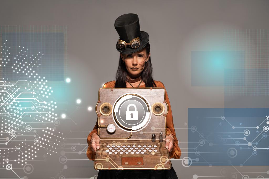 steampunk γυναίκα στην κορυφή καπέλο με γυαλιά που δείχνουν vintage laptop με την εικόνα ασφάλειας στο διαδίκτυο απομονώνονται σε γκρι - Φωτογραφία, εικόνα