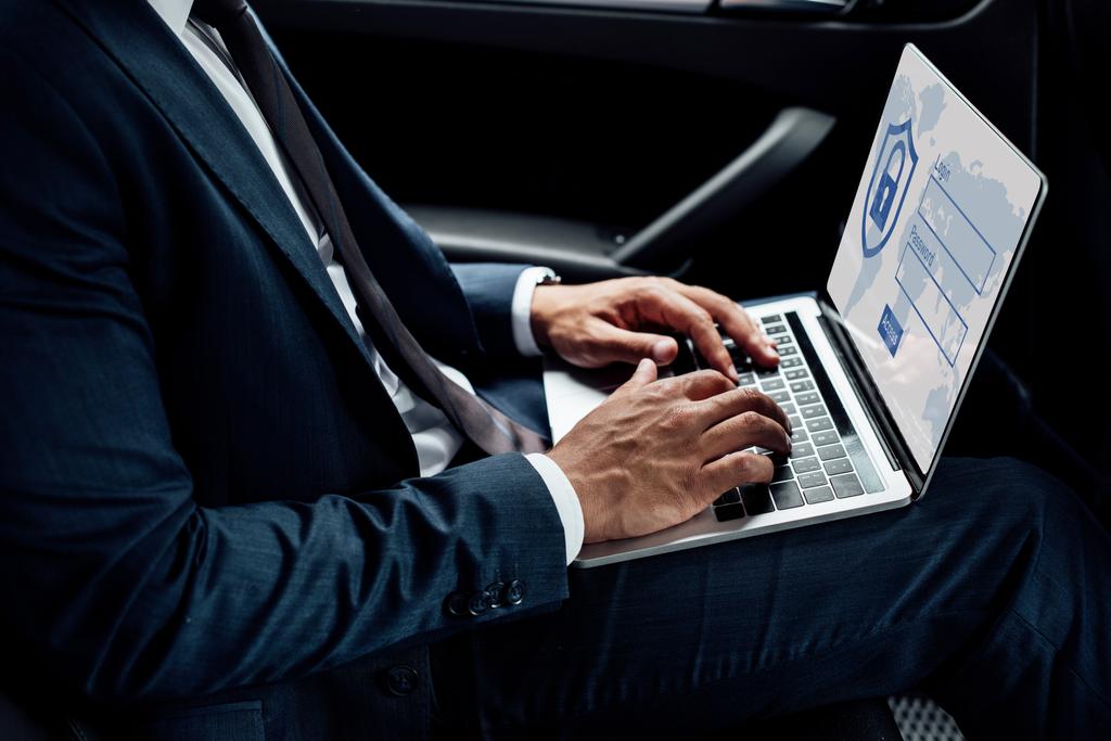 részleges kilátás afro-amerikai üzletember használja laptop internet biztonsági illusztráció autóban - Fotó, kép