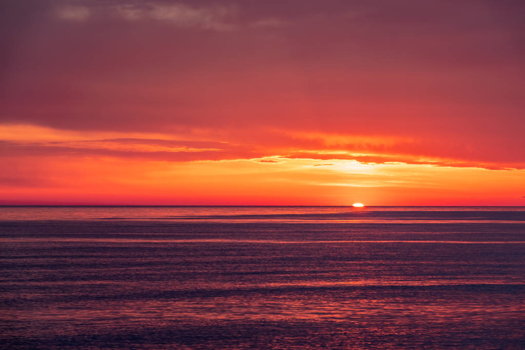Kaunis punainen ja oranssi auringonlasku meren yllä. Aurinko laskee meren yli.
. - Valokuva, kuva
