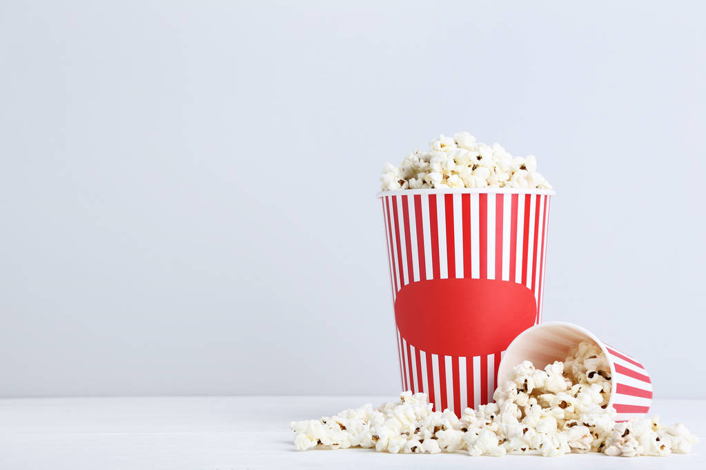 Popcorn in gestreepte emmers op grijze achtergrond - Foto, afbeelding
