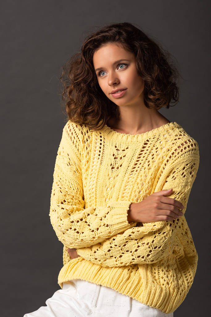 zasněný-kudrnatá žena ve žlutém pleteným svetru na černém pozadí - Fotografie, Obrázek