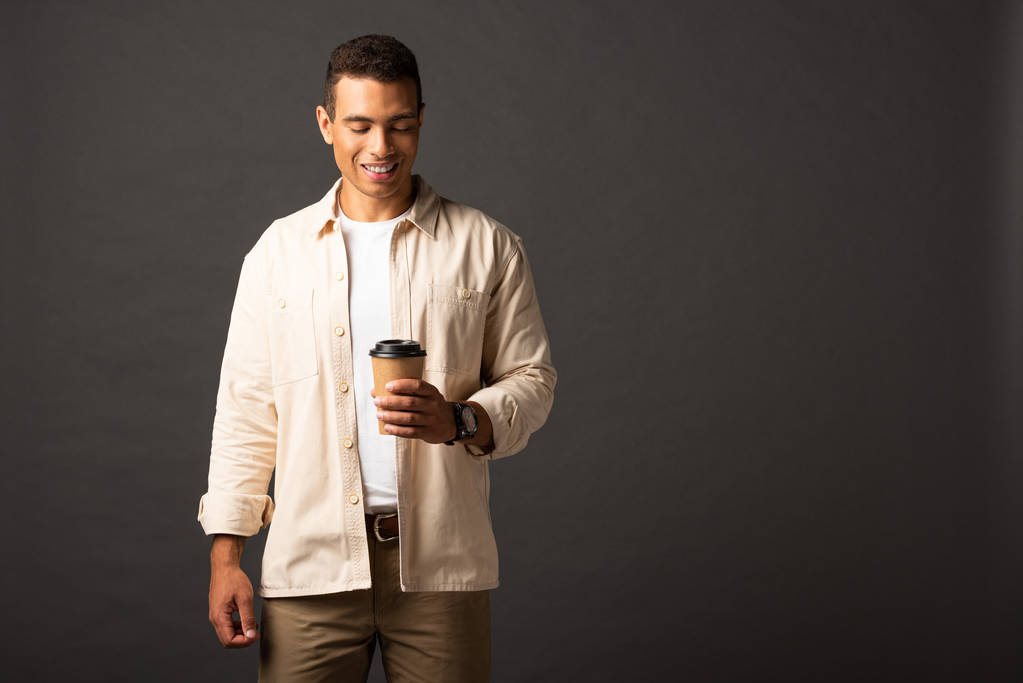 šťastný fešák Smíšené rasy v béžové košili s kávou na černém pozadí - Fotografie, Obrázek