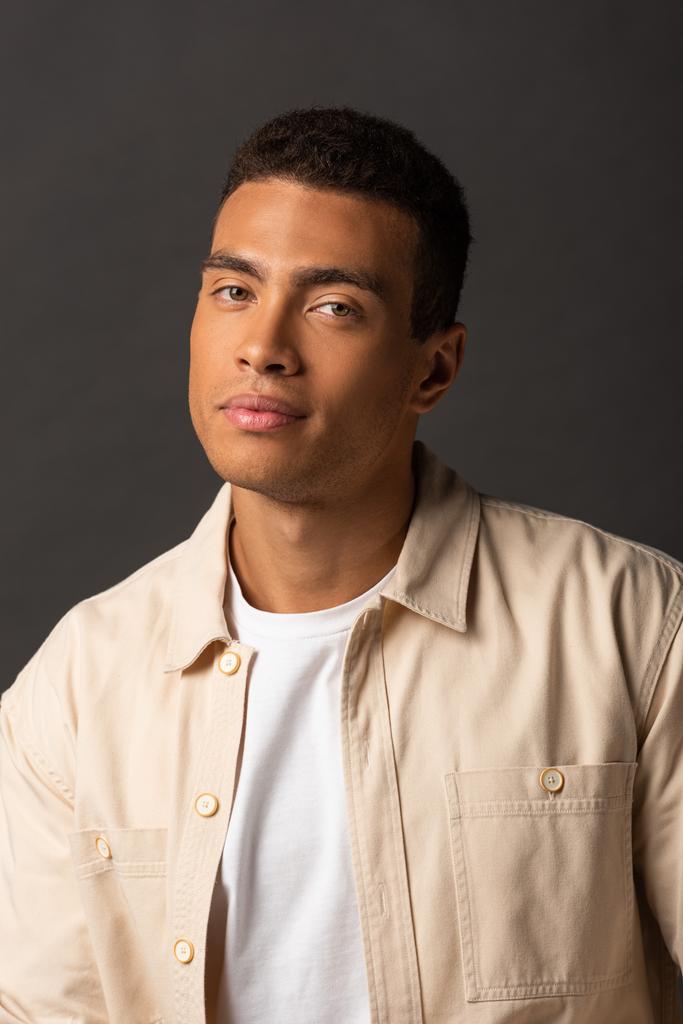 handsome mixed race man in beige shirt on black background - Photo, Image