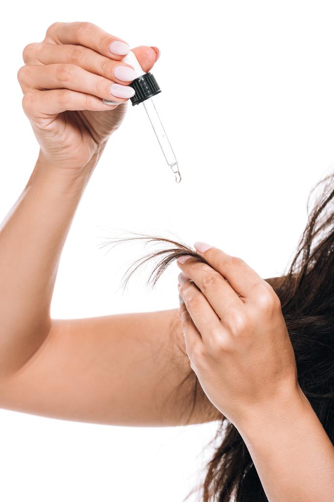 частковий вид брюнетки красива жінка з пошкодженим волоссям, що тримає олію ізольовано на білому
 - Фото, зображення