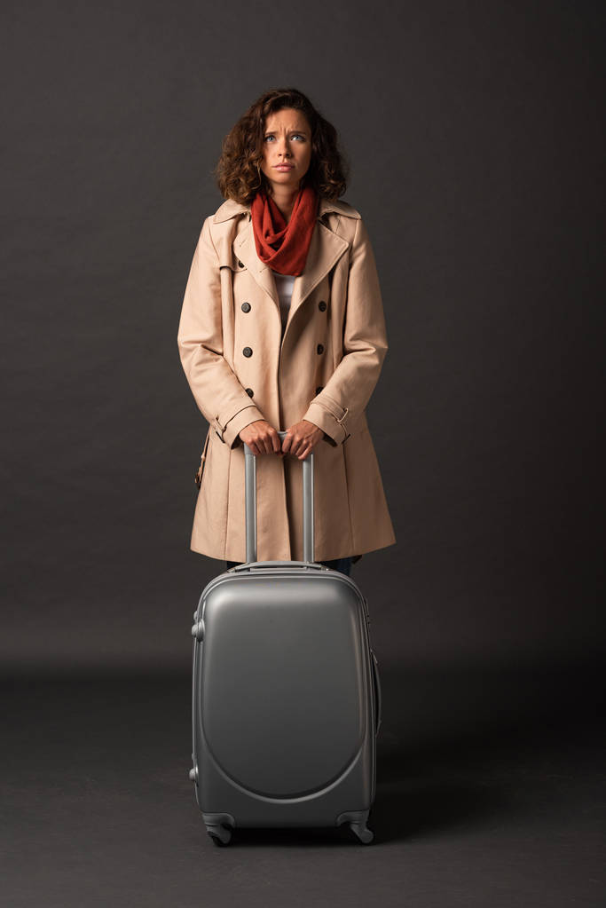 ideges elegáns nő viharkabát és sálat gazdaság fogantyú bőrönde a fekete háttér - Fotó, kép