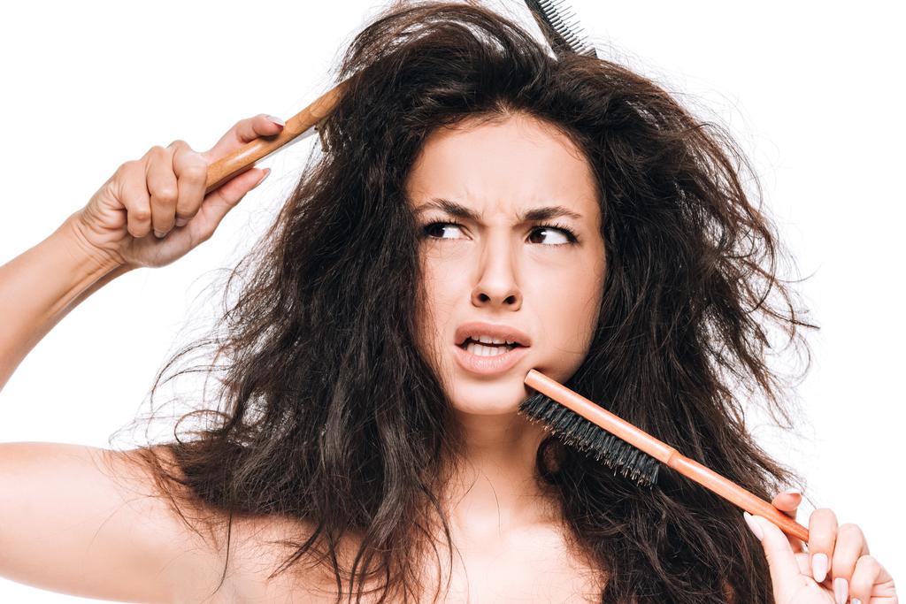 confusa donna bruna con pettini in capelli ondulati indisciplinati distogliendo lo sguardo isolato sul bianco
 - Foto, immagini