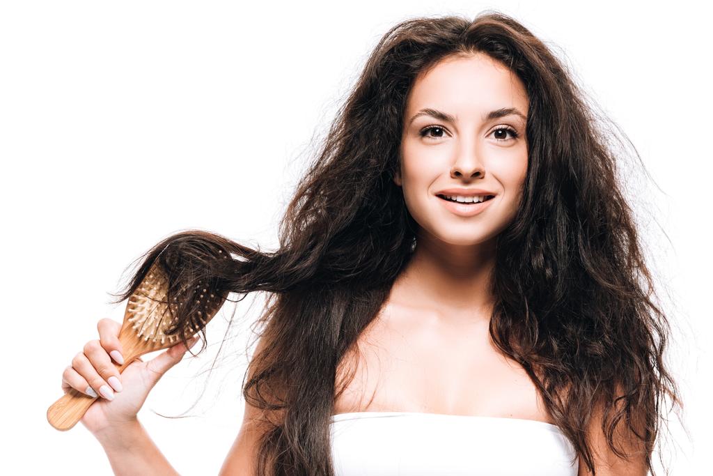 smiling brunette woman styling curly hair with hairbrush isolated on white - Photo, Image