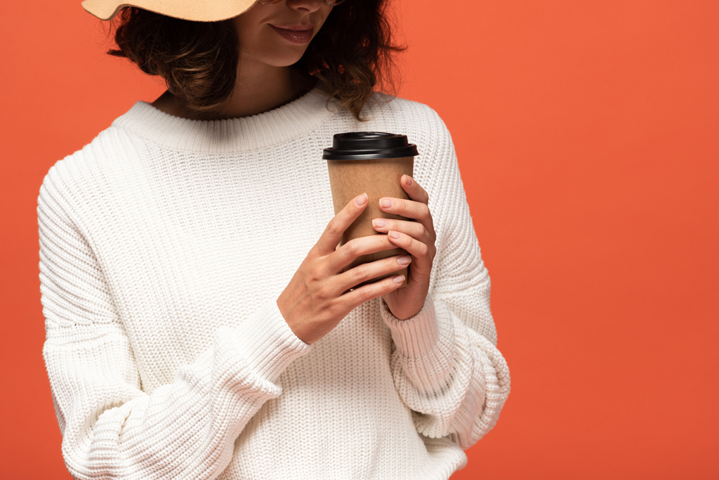 cropped view of woman in hat holding coffee to go isolated on orange - Photo, Image