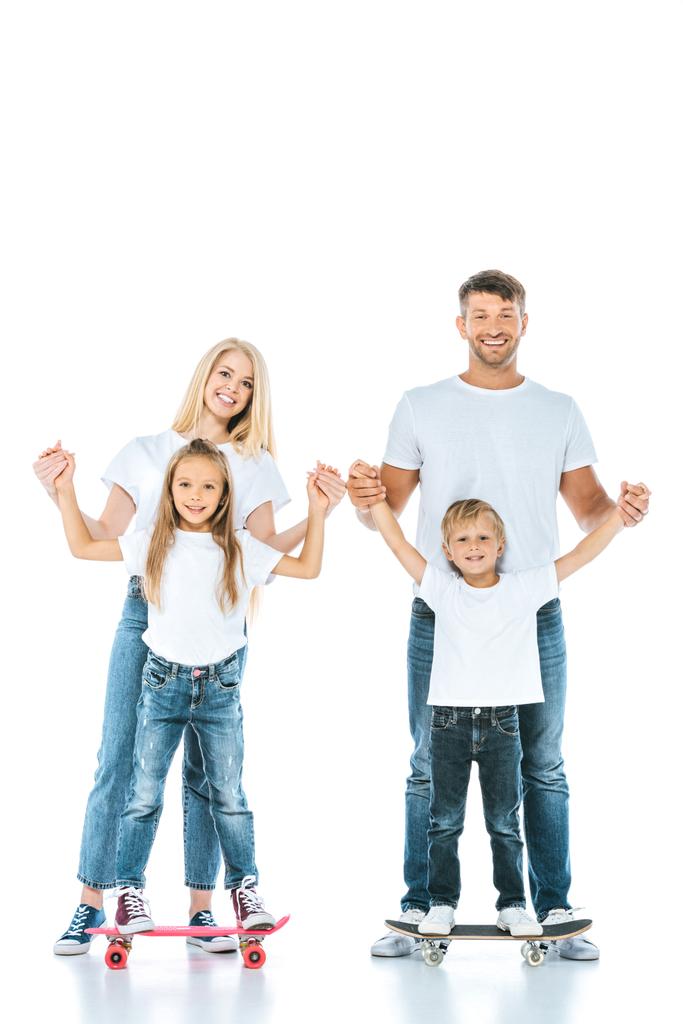 happy parents holding hands of son and daughter riding penny boards on white - Photo, Image