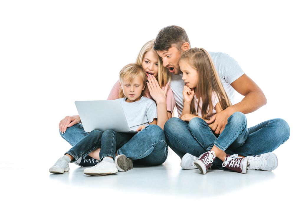 zaskoczeni rodzice patrząc na laptopa w pobliżu dzieci na białym  - Zdjęcie, obraz