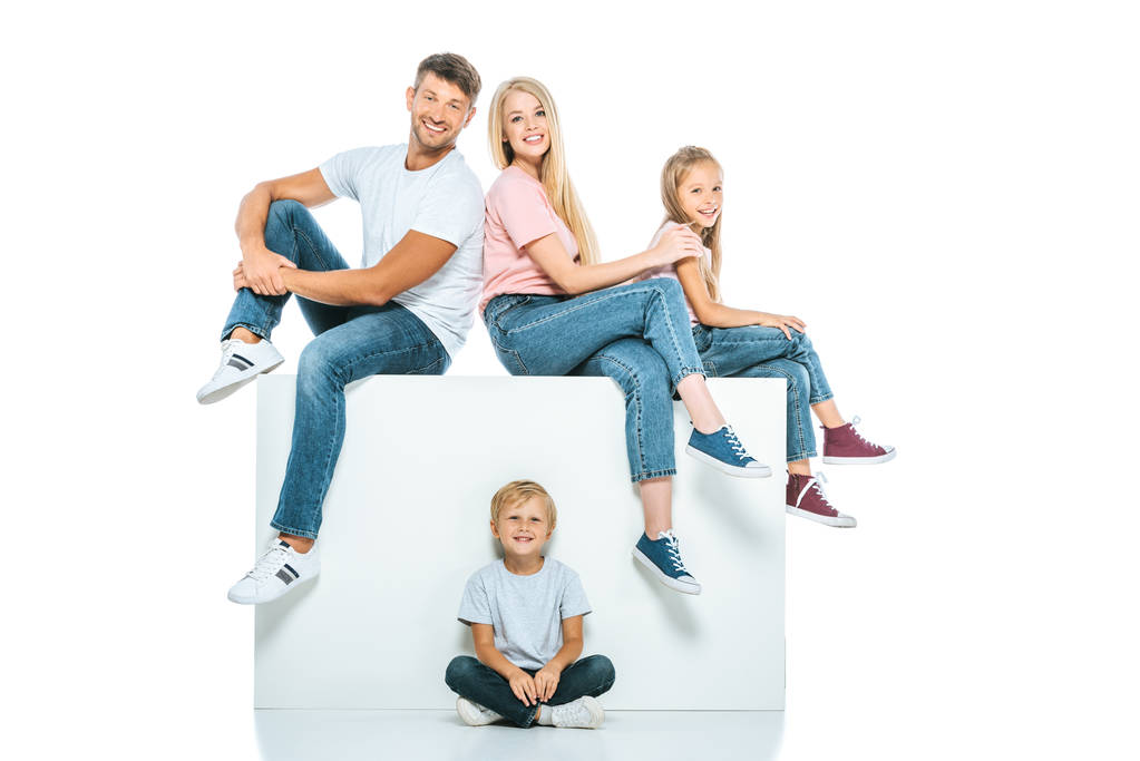 família feliz sentado no cubo e olhando para a câmera no branco
 - Foto, Imagem