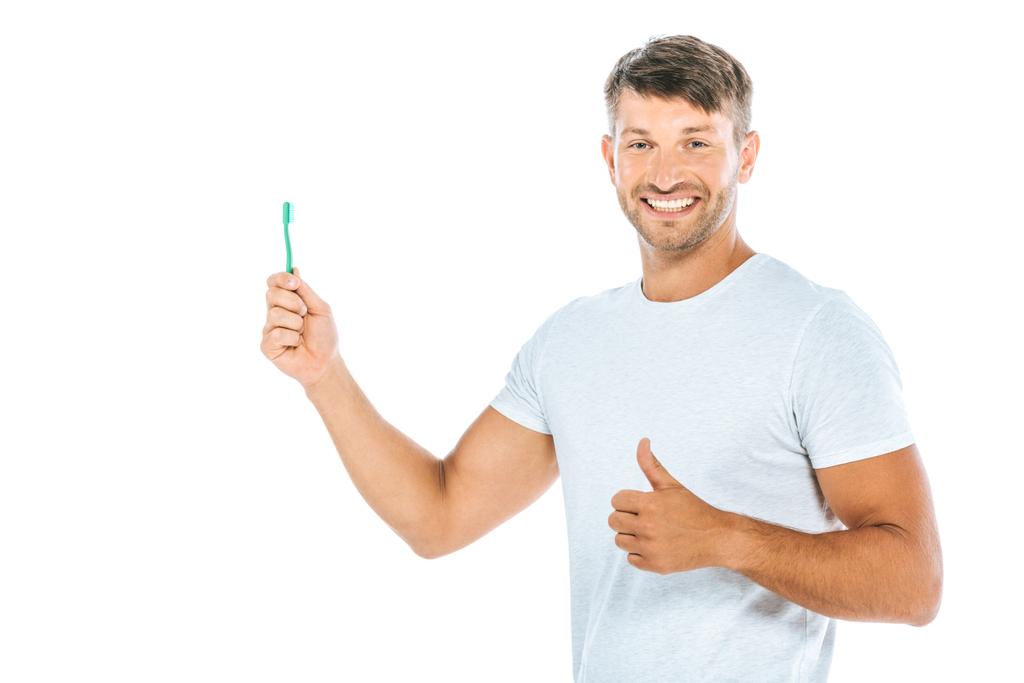 歯ブラシを持った陽気な男が親指を白地に隔離し  - 写真・画像