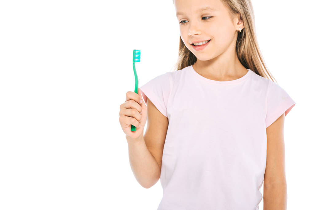 happy kid looking at toothbrush and smiling isolated on white  - Photo, Image