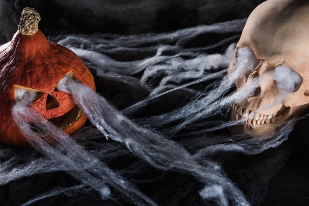 espeluznante cráneo humano y calabaza de Halloween tallada sobre fondo negro
 - Foto, imagen