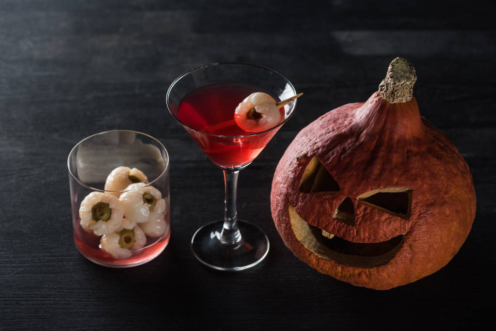 kísérteties faragott Halloween sütőtök és piros koktél, fekete háttér - Fotó, kép