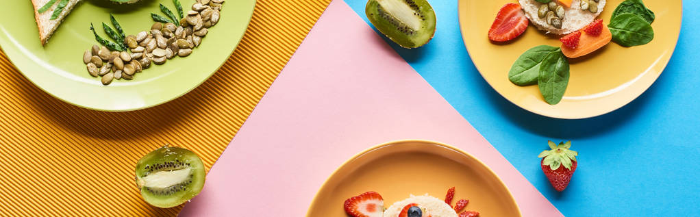 Teller mit ausgefallenen Tieren aus Kinderfrühstück auf blauem, gelbem und rosa Hintergrund - Foto, Bild