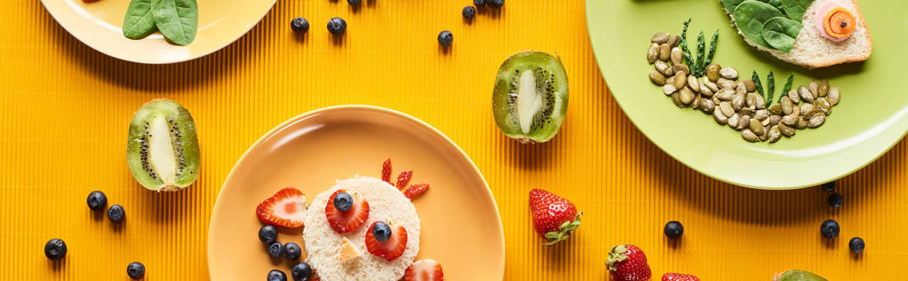 Teller mit ausgefallenen Tieren aus Lebensmitteln auf farbenfrohem orangefarbenem Hintergrund, Panoramaaufnahme - Foto, Bild
