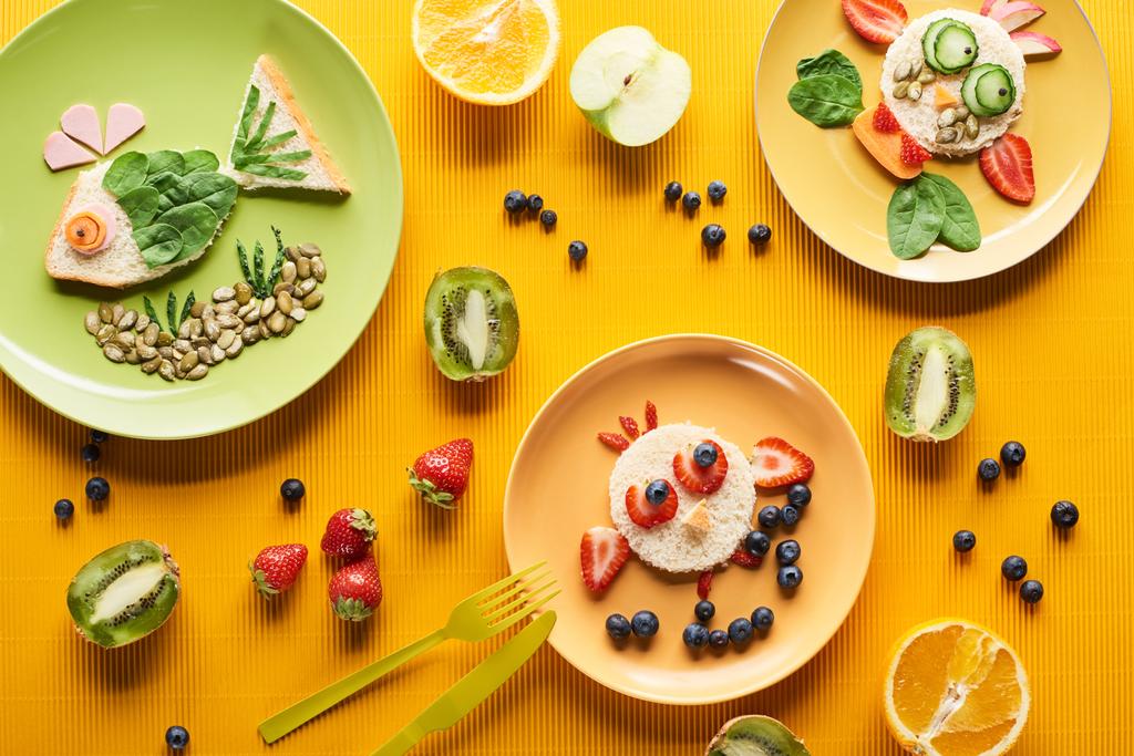вид зверху на тарілки з вишуканими тваринами з їжі на барвистому помаранчевому фоні
 - Фото, зображення