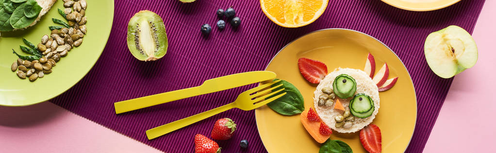 вид зверху на тарілки з вишуканими тваринами з їжі поблизу фруктів на фіолетовому фоні, панорамний знімок
 - Фото, зображення