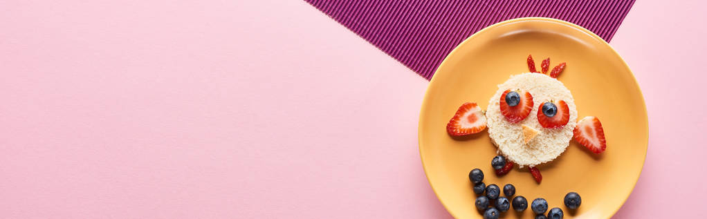 bovenaanzicht van de plaat met fancy vogel gemaakt van voedsel op roze en paarse achtergrond - Foto, afbeelding