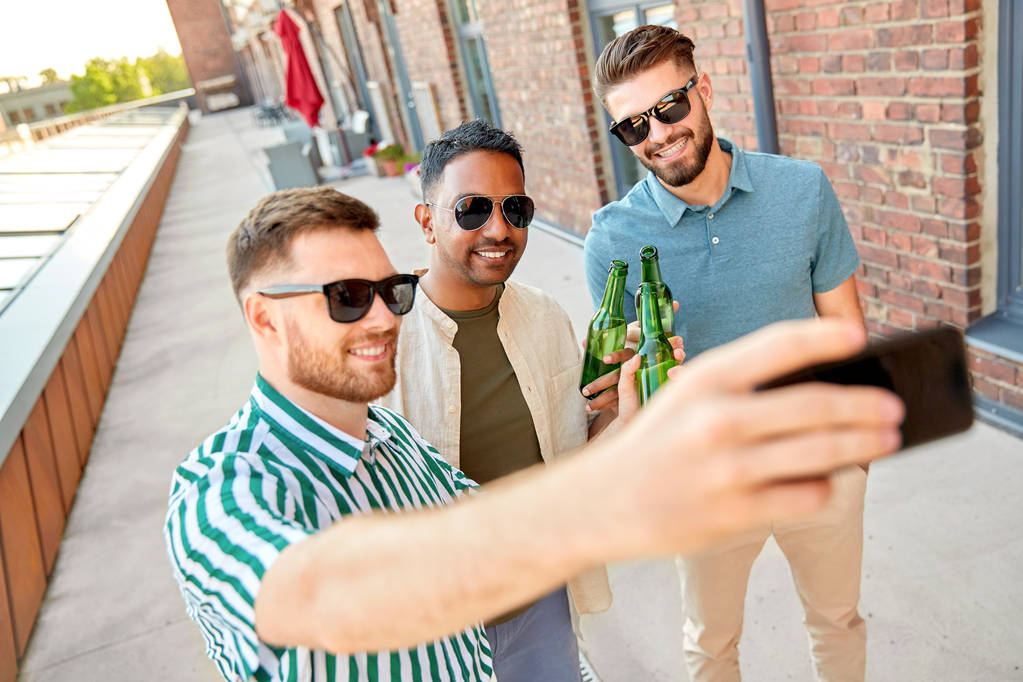 Erkekler bira içip, akıllı telefondan selfie çekiyorlar. - Fotoğraf, Görsel