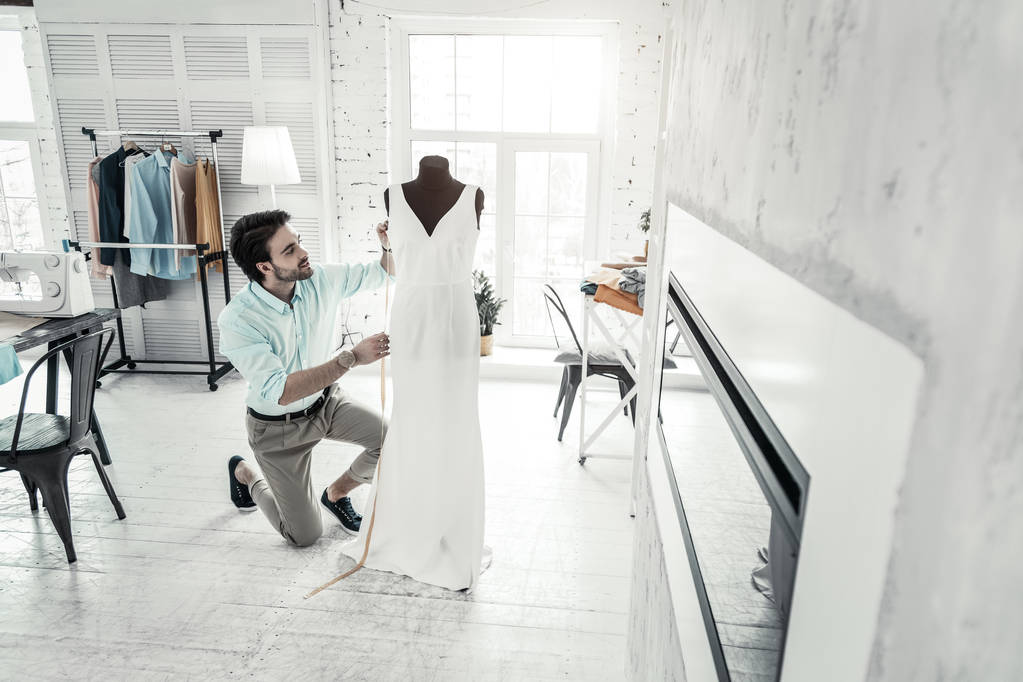 Позитивная брюнетка мужчина смотрит на белое платье
 - Фото, изображение