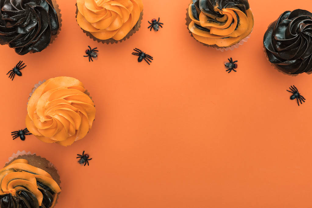 Widok z góry na pyszne Halloween Cupcakes z pająkami na pomarańczowym tle z kopią przestrzeni - Zdjęcie, obraz