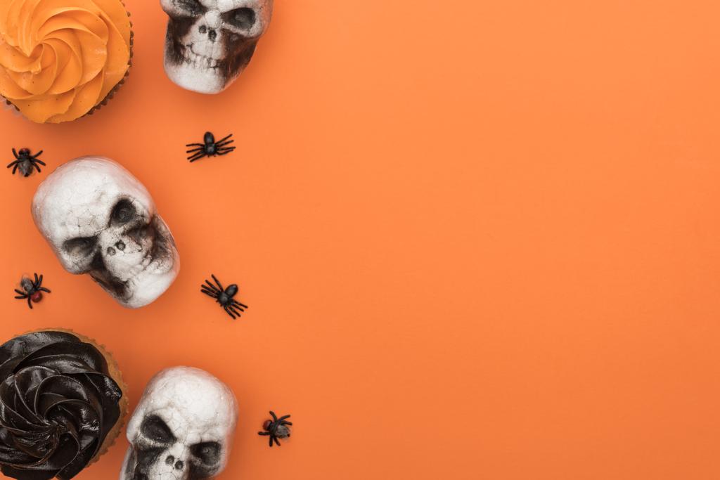 vista superior de cupcakes, crânios decorativos e aranhas em fundo laranja com espaço de cópia
 - Foto, Imagem