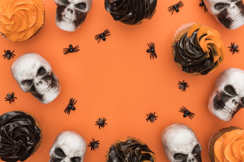 top view of delicious Halloween cupcakes with spiders and skulls on orange background with copy space - Photo, Image