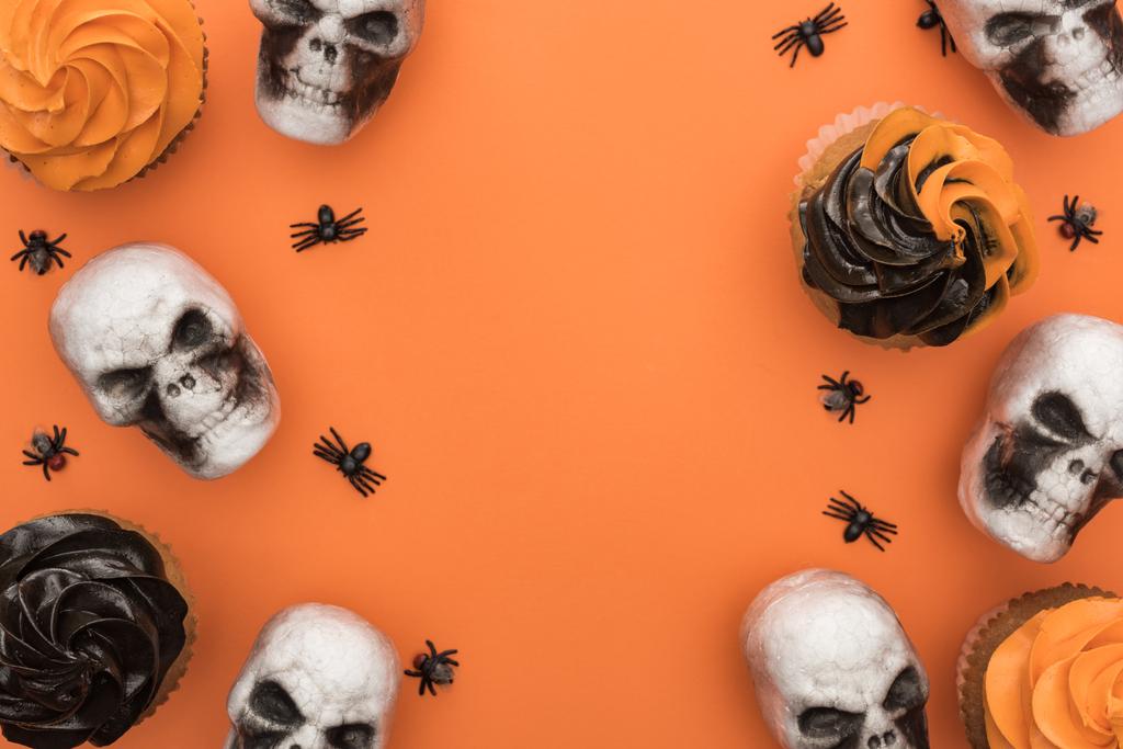 top view of tasty Halloween cupcakes with spiders and skulls on orange background with copy space - Photo, Image
