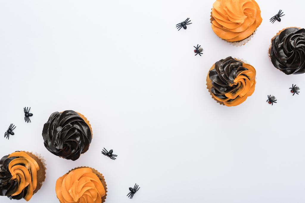 Draufsicht auf köstliche Halloween-Cupcakes mit Spinnen und Totenköpfen isoliert auf weiß mit Kopierraum - Foto, Bild