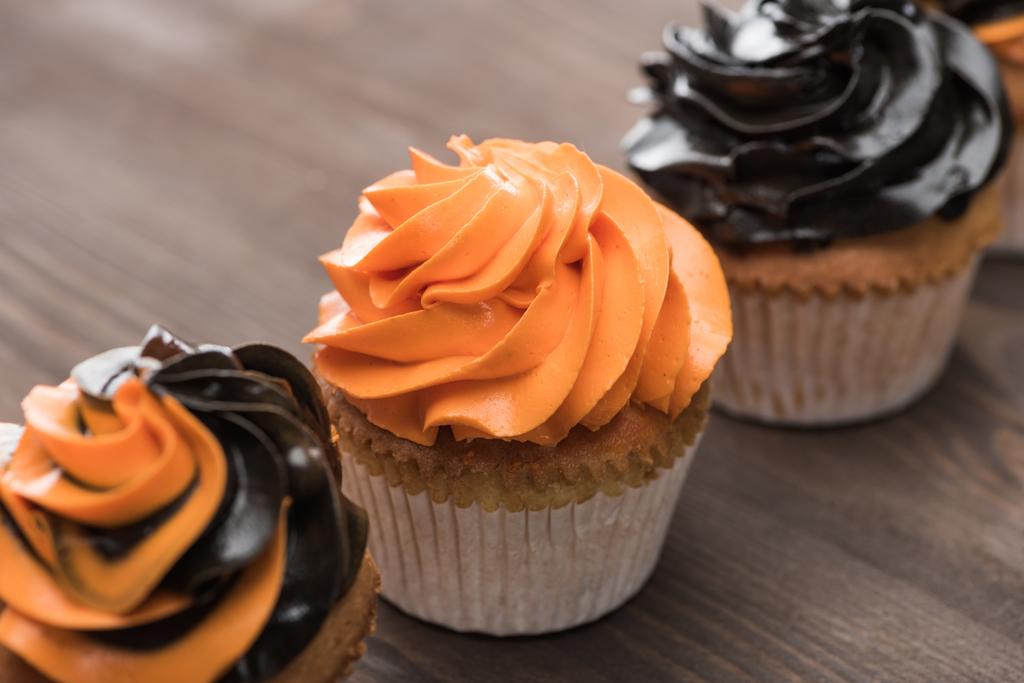 leckere halloween schwarze und orangefarbene Cupcakes auf Holztisch - Foto, Bild