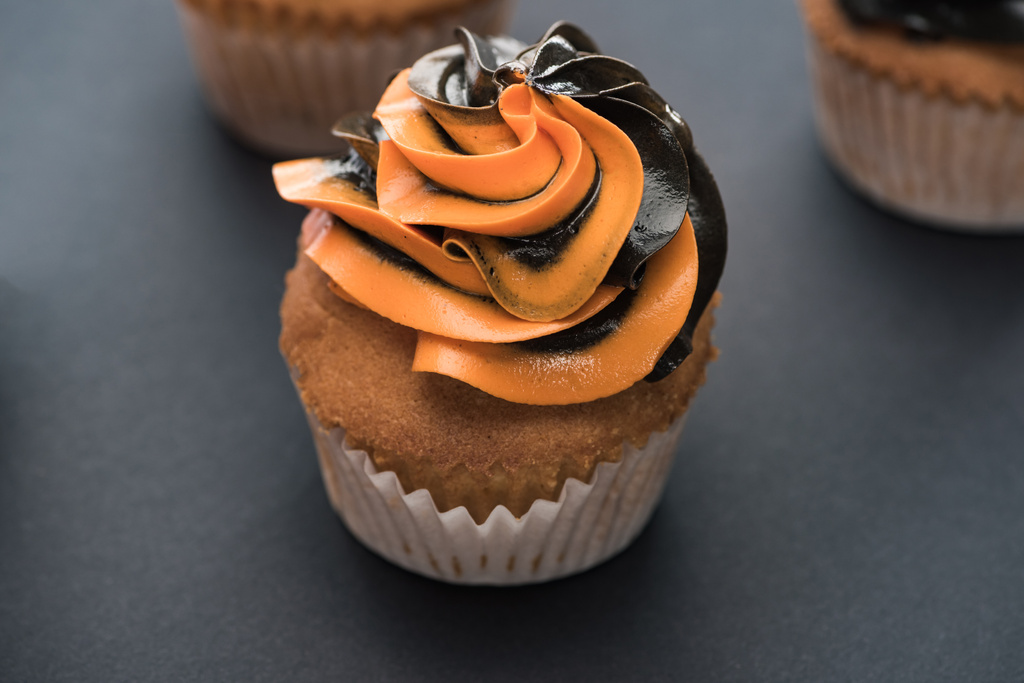 selective focus of delicious Halloween orange cupcake on black background - Photo, Image