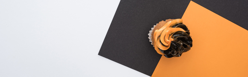 вид сверху на вкусный кекс Хэллоуин на черном, оранжевом и белом фоне с копировальным пространством, панорамный снимок
 - Фото, изображение