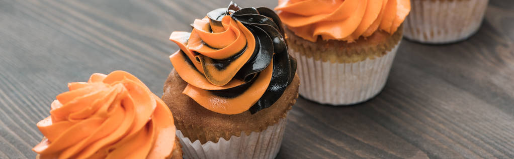 ízletes Halloween fekete-narancssárga cupcakes a fából készült asztal, panoráma shot - Fotó, kép