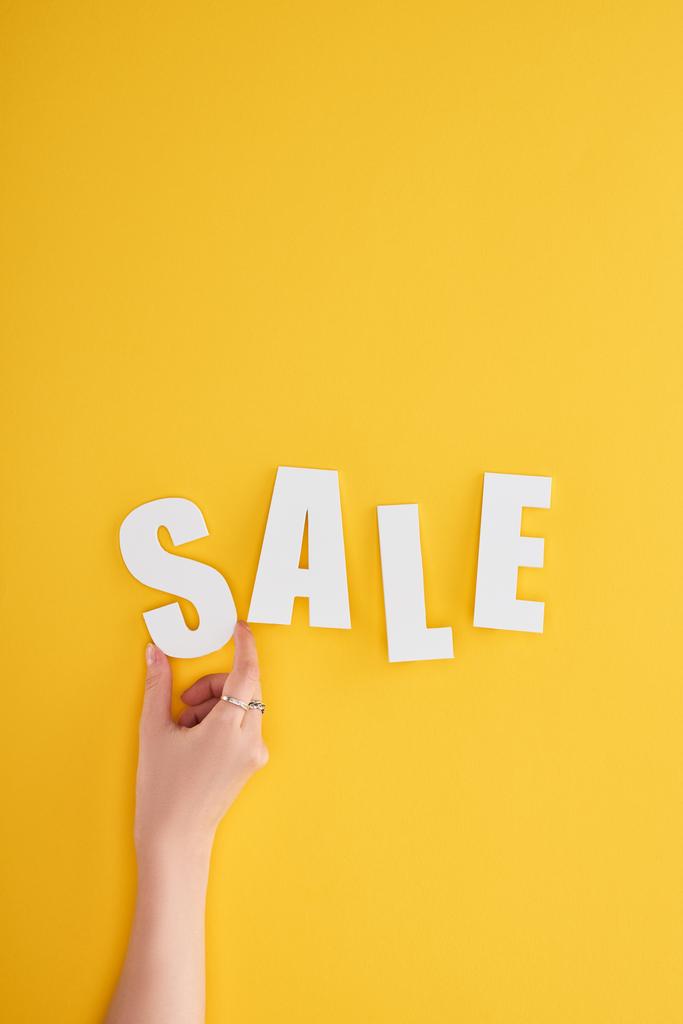 bijgesneden weergave van vrouw met verkoop belettering op gele achtergrond - Foto, afbeelding