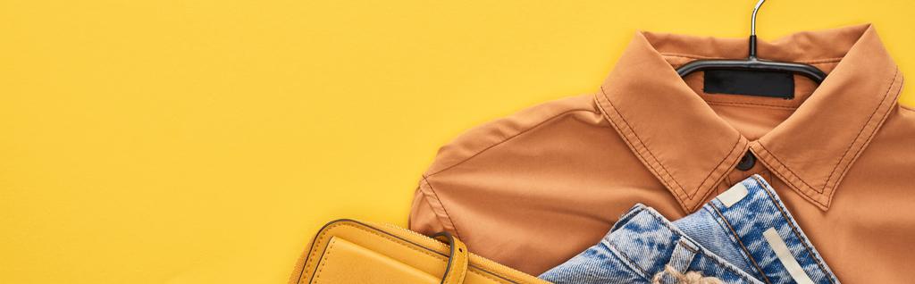top view of bag, shirt and jeans isolated on yellow - Photo, Image