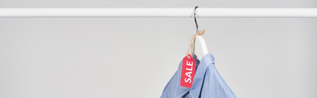camisa azul pendurada com etiqueta de venda isolada em branco, tiro panorâmico
 - Foto, Imagem