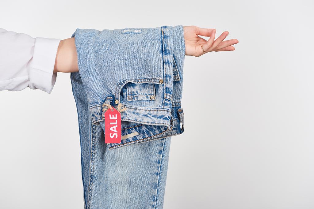 abgeschnittene Ansicht einer Frau mit hängenden Jeans und Verkaufsetikett isoliert auf weiß - Foto, Bild