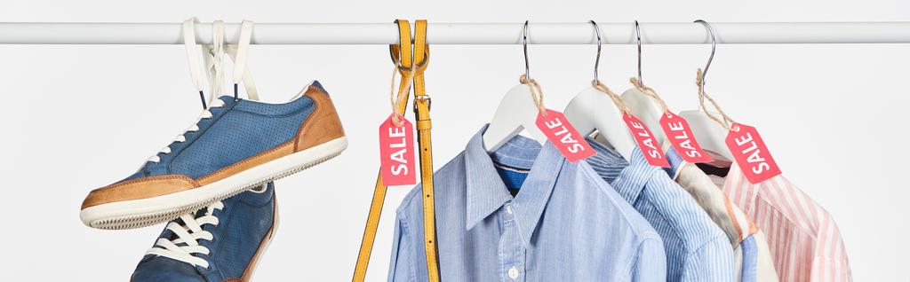 Turnschuhe, Tasche und elegante Hemden hängen mit Verkaufsetiketten isoliert auf weißer, panoramischer Aufnahme - Foto, Bild