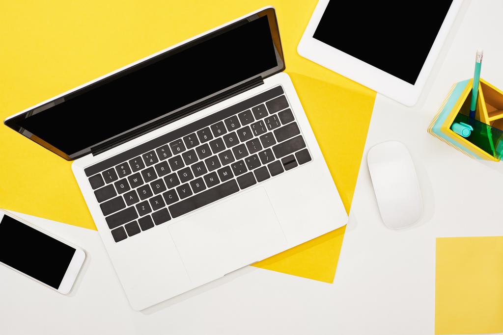 黄色と白の背景に空白の画面とコンピュータマウスを持つラップトップ、デジタルタブレット、スマートフォンのトップビュー - 写真・画像