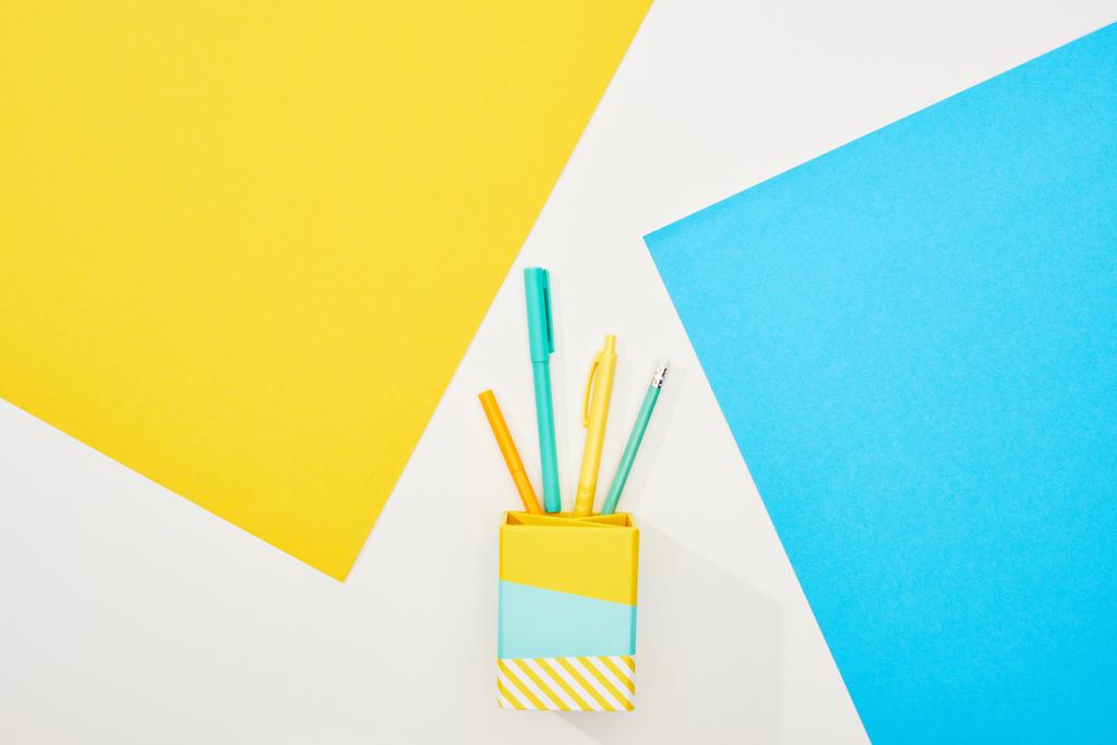 Zobrazení barevných kancelářských potřeb na žlutém, modrém a bílém pozadí - Fotografie, Obrázek