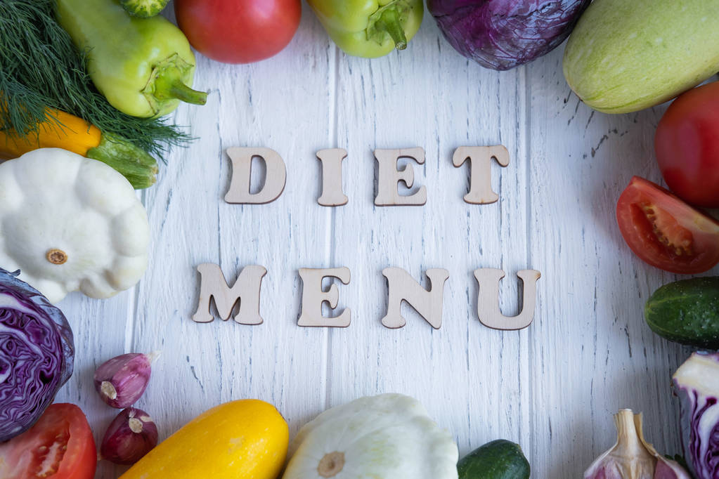 Het opschrift dieetmenu op een houten achtergrond met groenten in een cirkel. Goede en gezonde voeding zonder vlees. Groente menu voor gewichtsverlies. Uitzicht vanaf boven - Foto, afbeelding