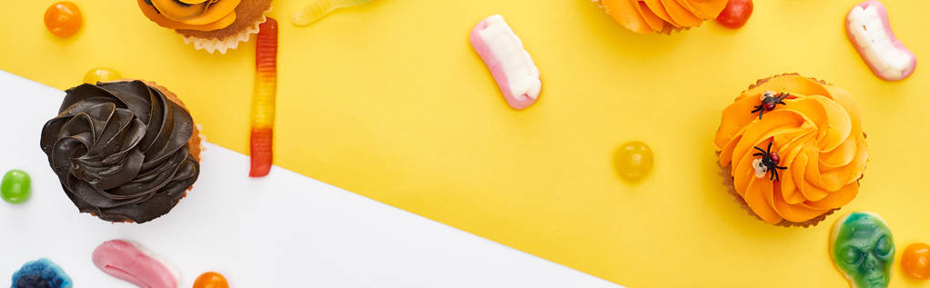 sarı ve beyaz arka plan üzerinde renkli sakızlı tatlılar ve cupcakes panoramik çekim, Cadılar Bayramı tedavi - Fotoğraf, Görsel
