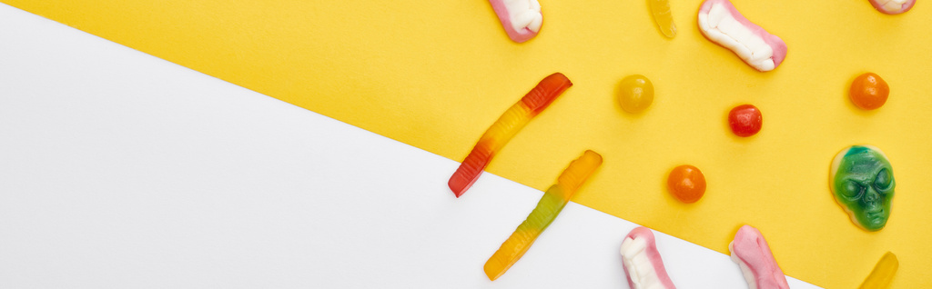 панорамний знімок барвистих жувальних цукерок на жовтому та білому тлі, Хеллоуїн
 - Фото, зображення